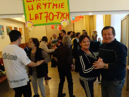 Tańczące pary pod papierowym napisem Zabawa w rytmie lat 70-tych w sali ozdobionej balonami