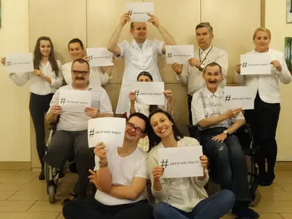 Mieszkańcy i pracownicy w bieli trzymają kartki z hasłem „#zrywamy więzy”