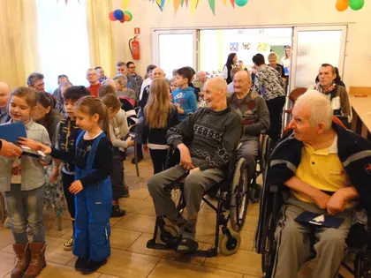 Dzieci rozdają mieszkańcom na wózkach własnoręcznie zrobione kartki świąteczne
