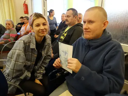 Młoda kobieta i mieszkaniec pozują z kartką z rysunkiem w czasie kolędowania