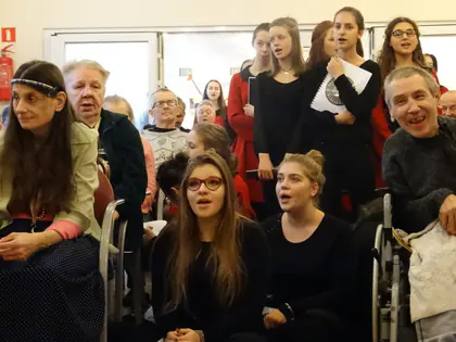 Licealistki śpiewają kolędy wśród mieszkańców siedzących w świetlicy