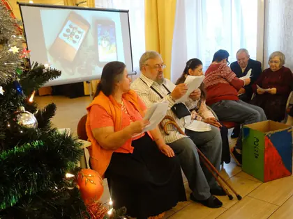 Mieszkańcy śpiewają kolędy z kartkami przy choince