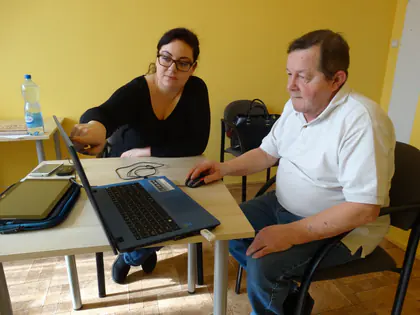 Prowadząca pokazuje mieszkańcowi obsługę laptopa podczas konsultacji