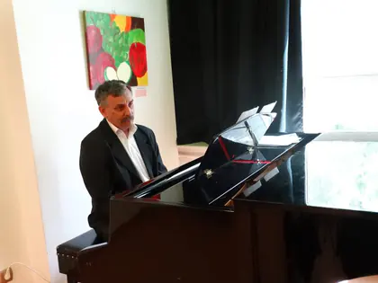 Pianista w czarnej marynarce gra na fortepianie