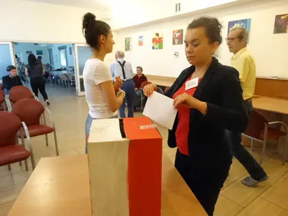 Opiekunka wrzuca kartę do urny podczas wyborów do Rady Mieszkańców