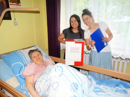Opiekunki z przenośną urną odwiedzają mieszkankę leżącą w łóżku, by mogła zagłosować
