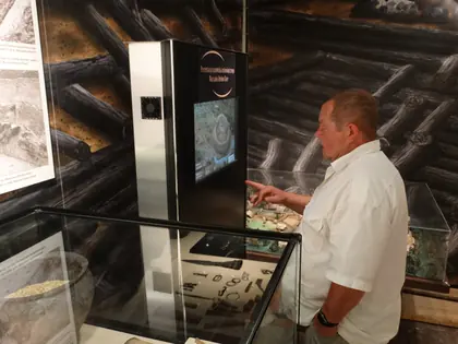 Mężczyzna ogląda interaktywny ekran z mapą na wystawie archeologicznej