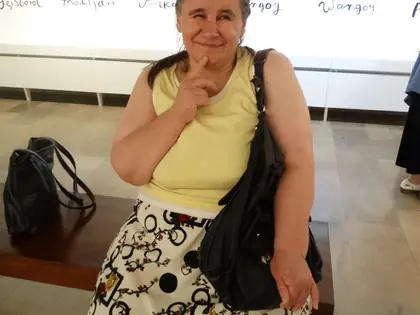Mieszkanka z palcem przy ustach pozuje na tle kolorowych karykatur