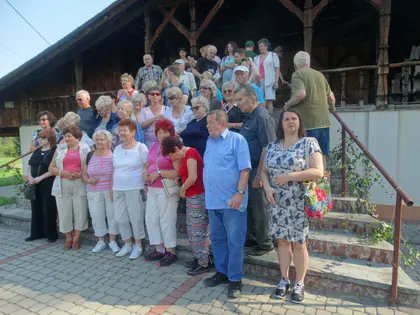 Grupa uczestników wyjazdu pozuje na schodach przed drewnianym budynkiem
