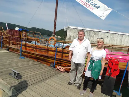 Mężczyzna i kobieta stoją na pomoście przy drewnianym statku nad Soliną