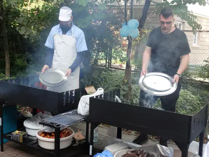 Dwaj kucharze przy grillu w ogrodzie trzymają metalowe tace