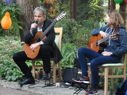 Dwóch gitarzystów gra i śpiewa w ogrodzie udekorowanym balonami