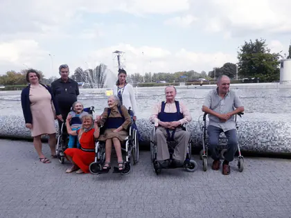 Mieszkańcy na wózkach i opiekunowie pozują przy fontannie nad Wisłą
