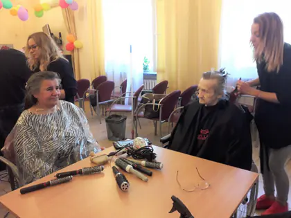 Fryzjerki układają włosy mieszkankom przy stole z lokówkami
