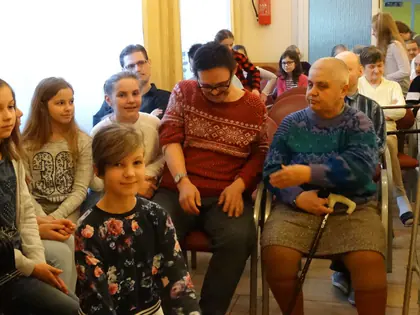 Dziewczynki siedzą wśród mieszkańców podczas kolędowania