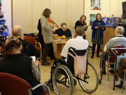 Skrzypaczka i gitarzysta grają kolędy przed mieszkańcami