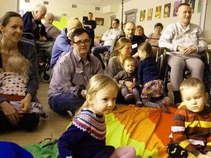 Mamy z małymi dziećmi i mieszkańcy siedzą wokół chusty animacyjnej