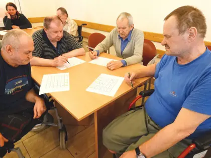 Mieszkańcy przy stole skreślają liczby na kartach do bingo