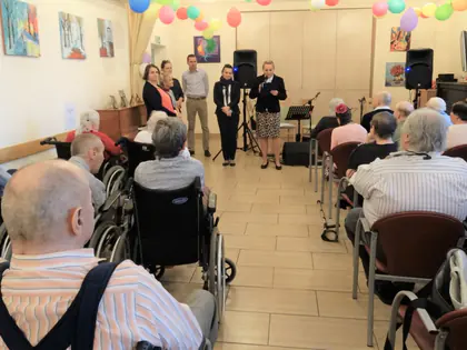 Mieszkańcy słuchają występu zespołu w świetlicy z balonami