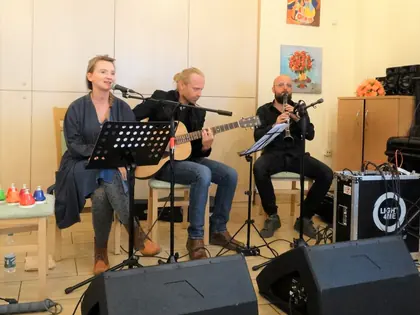 Wokalistka, gitarzysta i klarnecista grają w świetlicy