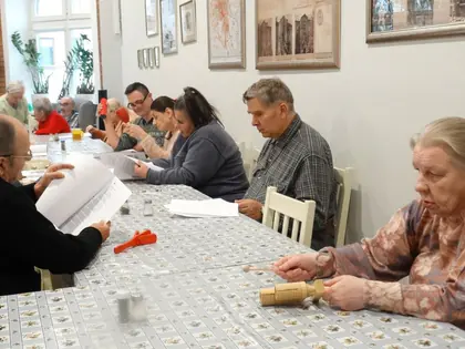 Seniorzy z dwóch domów przy stole podczas warsztatów muzycznych z instrumentami