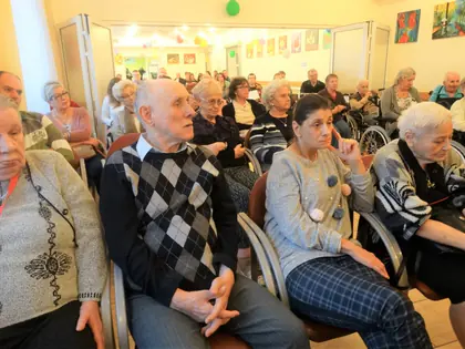 Mieszkańcy siedzą w rzędach i słuchają koncertu
