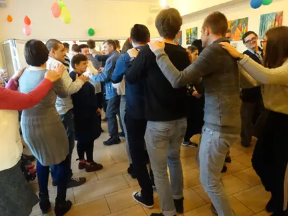 Mieszkańcy i młodzież tańczą w korowodzie w świetlicy z balonami