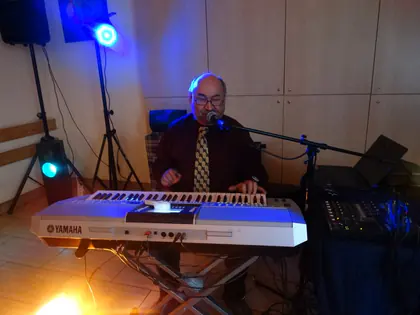 Muzyk gra na keyboardzie i śpiewa przy mikrofonie w kolorowym świetle