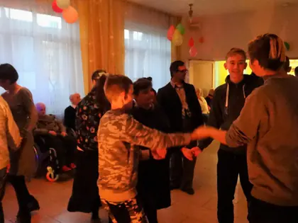 Chłopiec tańczy z mieszkańcem w świetlicy z balonami