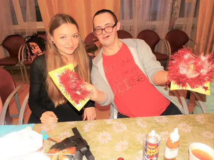 Studentka i mieszkaniec w okularach pokazują świąteczne ozdoby z papieru