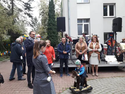 Goście pikniku przy scenie, dziecko na drewnianym koniku na kółkach