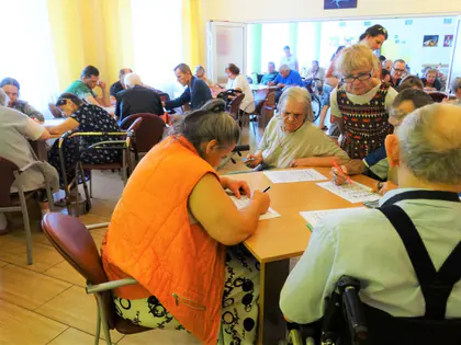 Mieszkańcy grają w bingo przy stołach w świetlicy