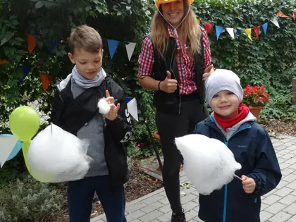 Dwaj chłopcy z watą cukrową i kobieta w kowbojskim kapeluszu na pikniku