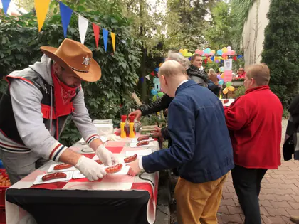 Mężczyzna w kowbojskim kapeluszu wydaje kiełbaski gościom