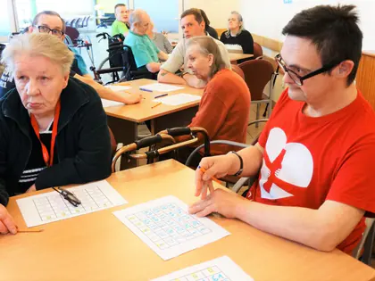 Mieszkanka i mieszkaniec w czerwonej koszulce przy kartach do bingo
