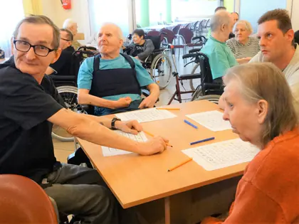 Mieszkańcy grają w bingo przy stole z kartami i długopisami