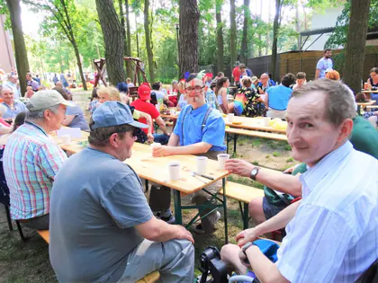 Mieszkańcy przy drewnianych stołach na pikniku w lesie