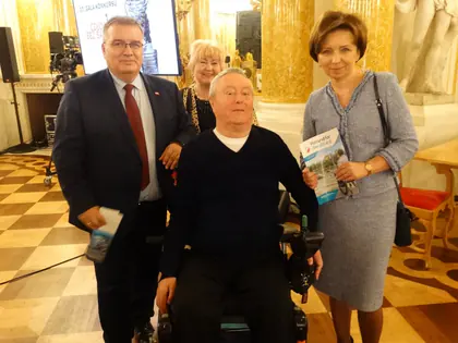 Laureat konkursu na wózku z gośćmi podczas gali w ozdobnej sali