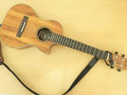 Ukulele z paskiem leżące na jasnym blacie