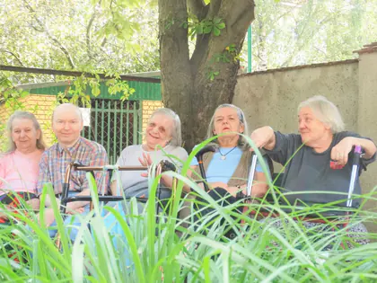 Mieszkańcy siedzą razem w ogrodzie sensorycznym pod drzewem