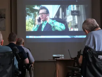 Mieszkańcy oglądają film wyświetlany na ekranie w świetlicy