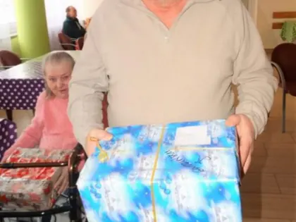 Mieszkaniec w czapce Mikołaja trzyma zapakowany prezent