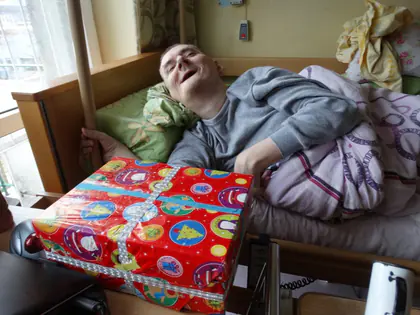 Mieszkaniec w łóżku z prezentem mikołajkowym w kolorowym papierze