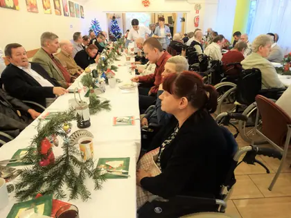 Mieszkańcy siedzą wzdłuż długiego wigilijnego stołu ze stroikami