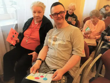 Mieszkanka i mieszkaniec w okularach pokazują wykonane kartki