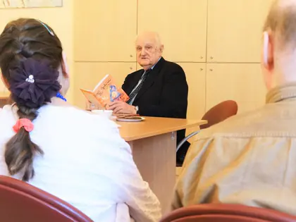 Poeta i satyryk czyta swoje utwory mieszkańcom przy stole w świetlicy