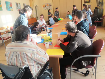 Mieszkańcy i harcerki wycinają serca z papieru przy długim stole