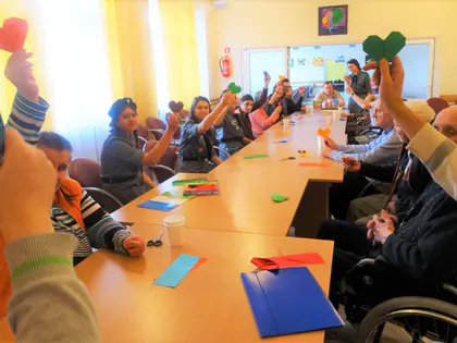 Mieszkańcy i harcerki unoszą serca złożone z papieru metodą origami
