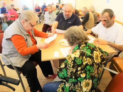 Mieszkańcy i goście z zaprzyjaźnionych domów grają w bingo przy stołach