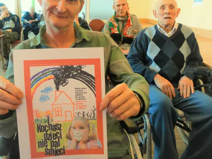 Mieszkaniec trzyma plakat akcji Kochasz dzieci, nie pal śmieci